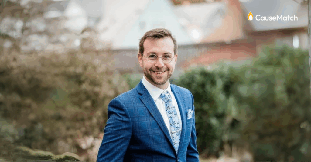 Tom Eisenman, CauseMatch Executive Sales associate, is standing in front of foliage for a professional headshot.